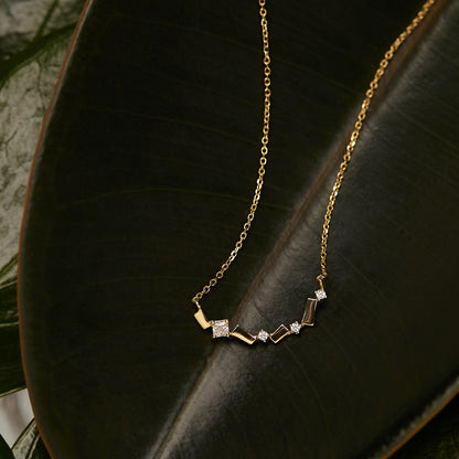 Wholesale S925 18K gold plated bar zircon necklace displayed on dark green leaf