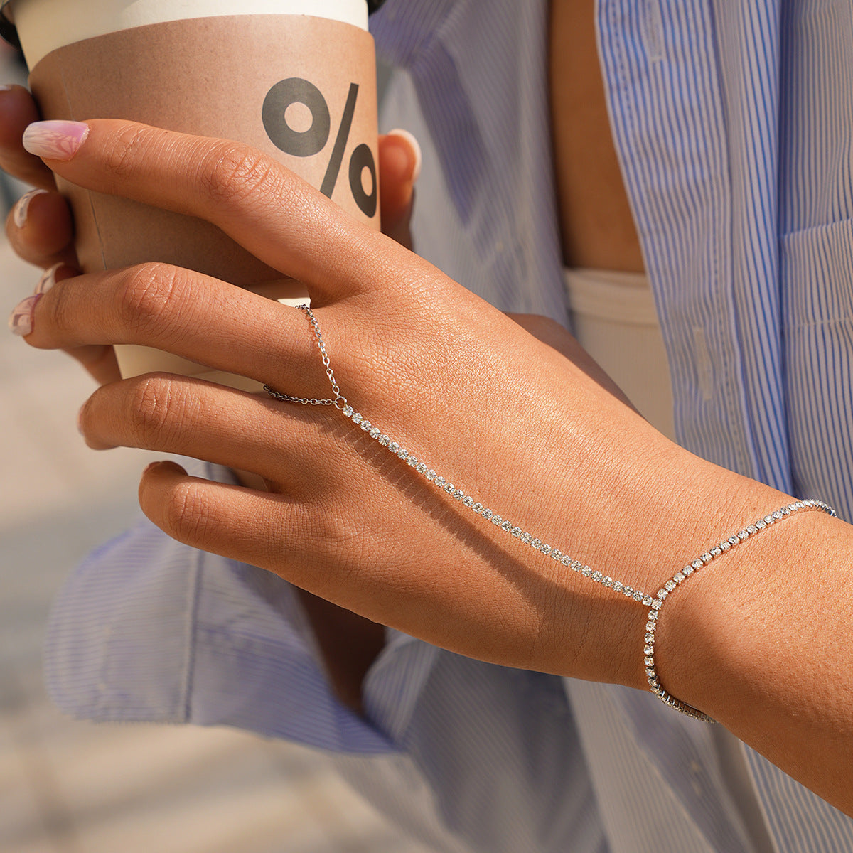 Silver cubic zirconia hand chain bracelet worn with a casual striped shirt