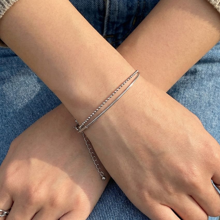 Silver layered bracelet on wrist snake chain and ball chain minimal style