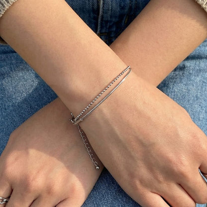 Silver layered bracelet on wrist snake chain and ball chain minimal style