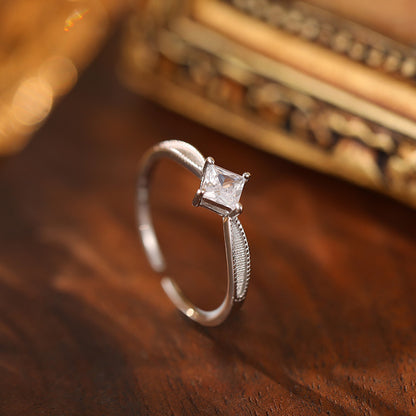 Square CZ ring in silver, delicately set on a wooden surface.