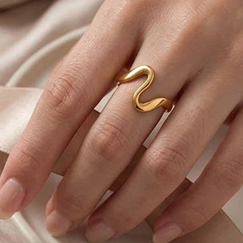 Polished gold stainless steel wave ring worn as a minimalist statement accessory