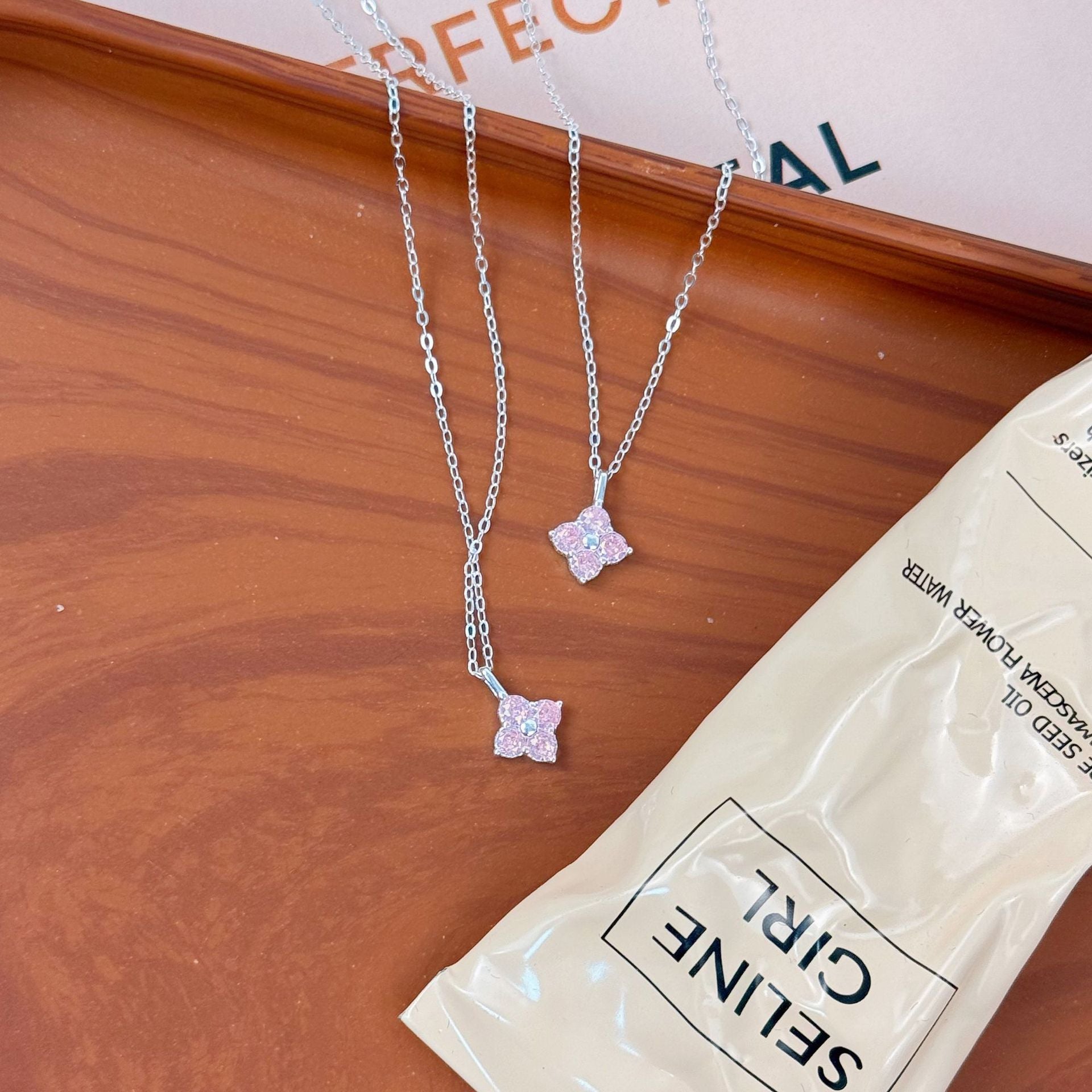 Two wholesale 925 sterling silver pink zircon four leaf clover pendant necklaces on display.