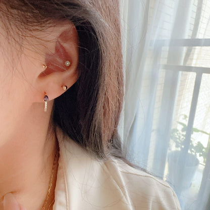 Woman wearing S925 sterling silver 18K gold plated teardrop CZ huggie earrings with purple cubic zirconia stone