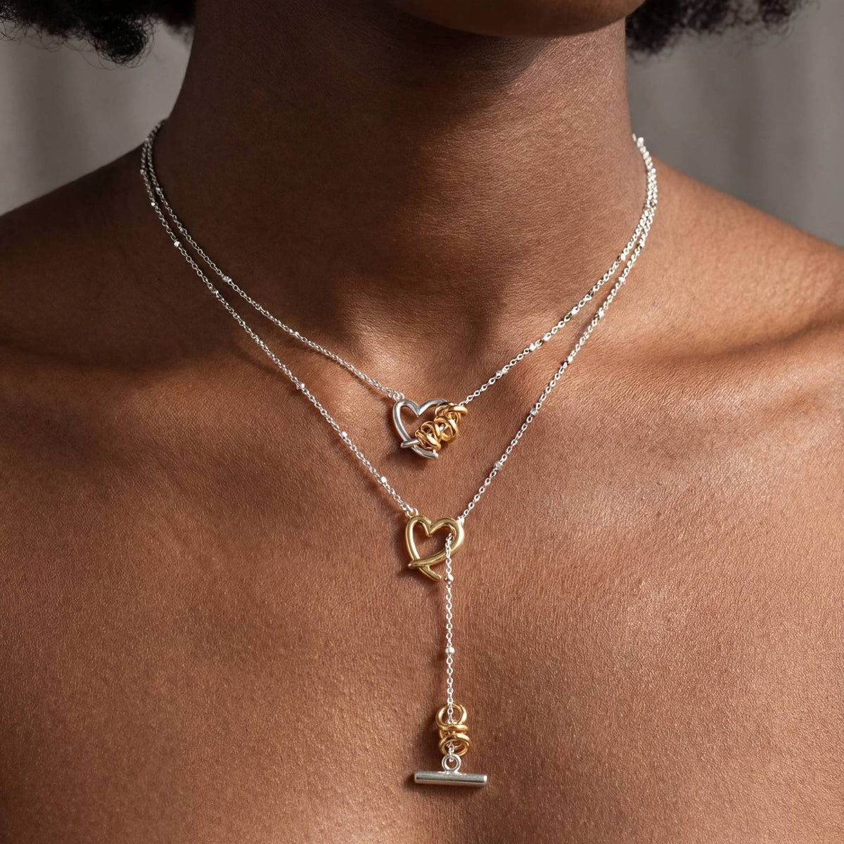 Two separately sold heart necklaces shown layered
