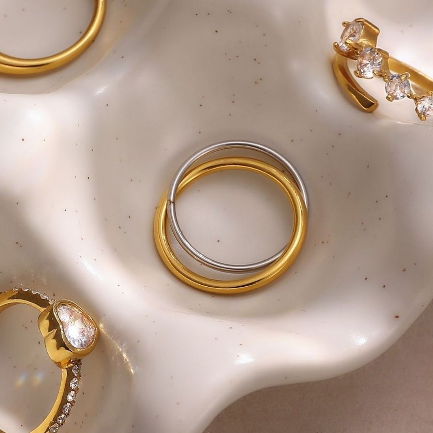 Two tone stainless steel ring set in gold and silver displayed on ceramic tray