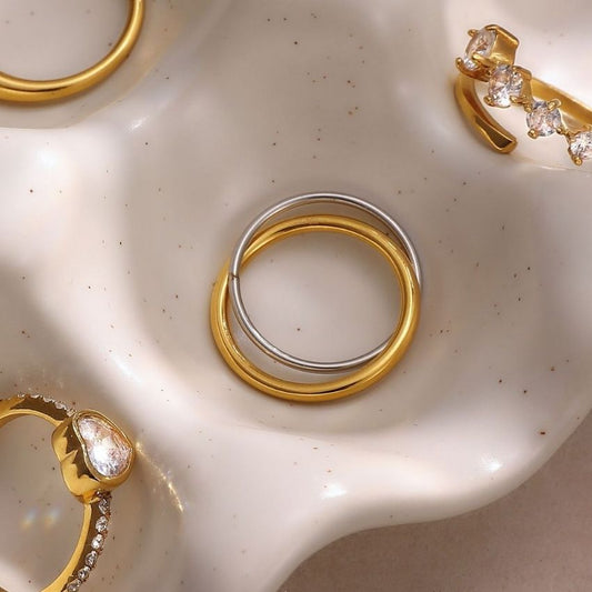 Two tone stainless steel ring set in gold and silver displayed on ceramic tray