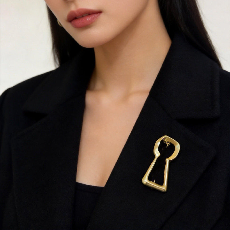 Gold keyhole shaped brooch styled on a black blazer lapel