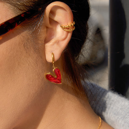 Red heart drop earring worn close up fashion accessory