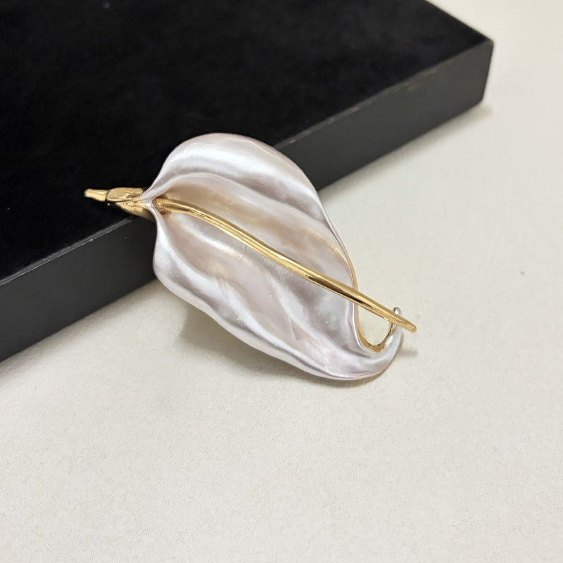 Angled view of a white enamel iris flower leaf brooch