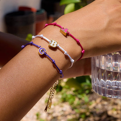 Model wearing three personalized letter bracelets with A, B, and C enamel charms. These wholesale 18k gold plated friendship bracelets are ideal as custom jewelry gifts for her or boutique resale.