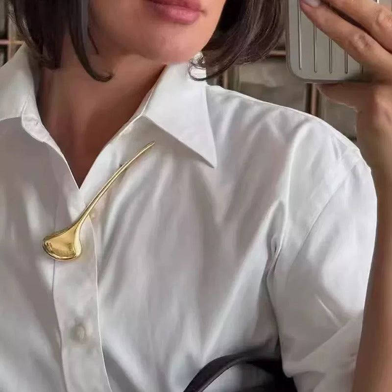 Gold tone ginkgo leaf brooch styled on a white shirt lapel