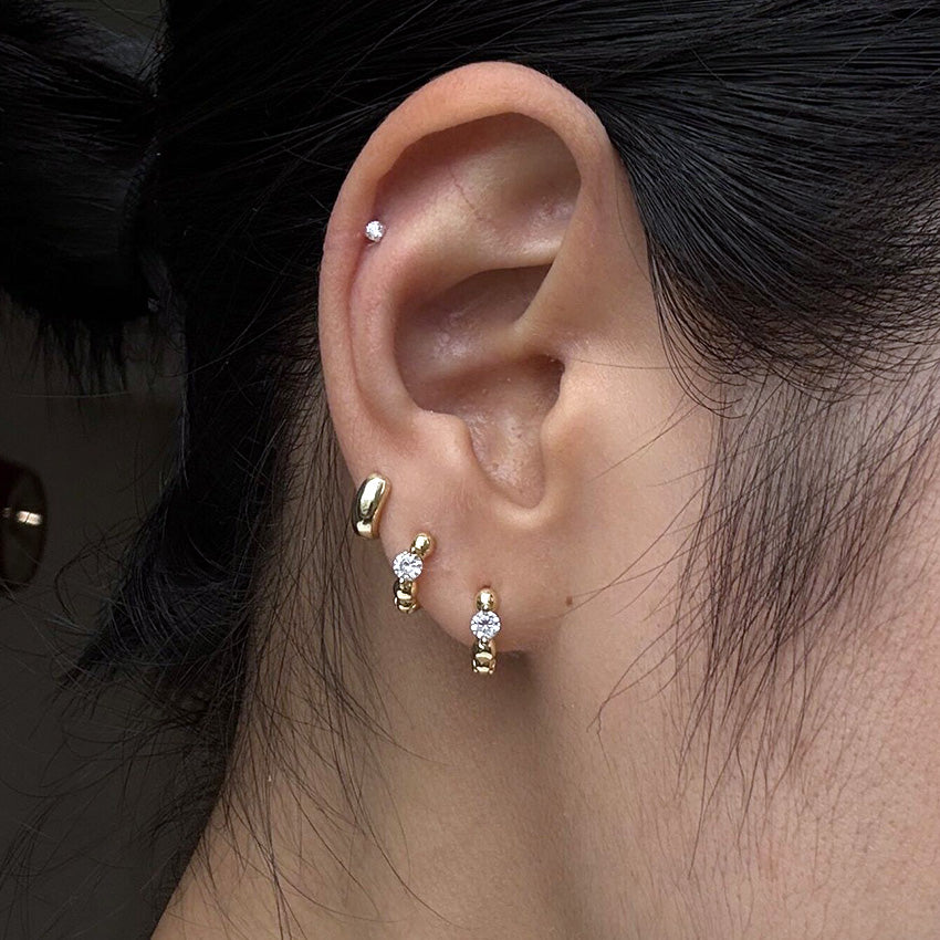 Woman wearing S925 sterling silver huggie earrings with cubic zirconia and 18K gold plating