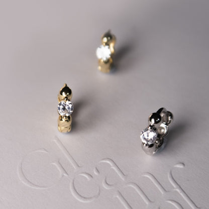 Close up of sterling silver huggie earrings featuring sparkling cubic zirconia and polished bead details