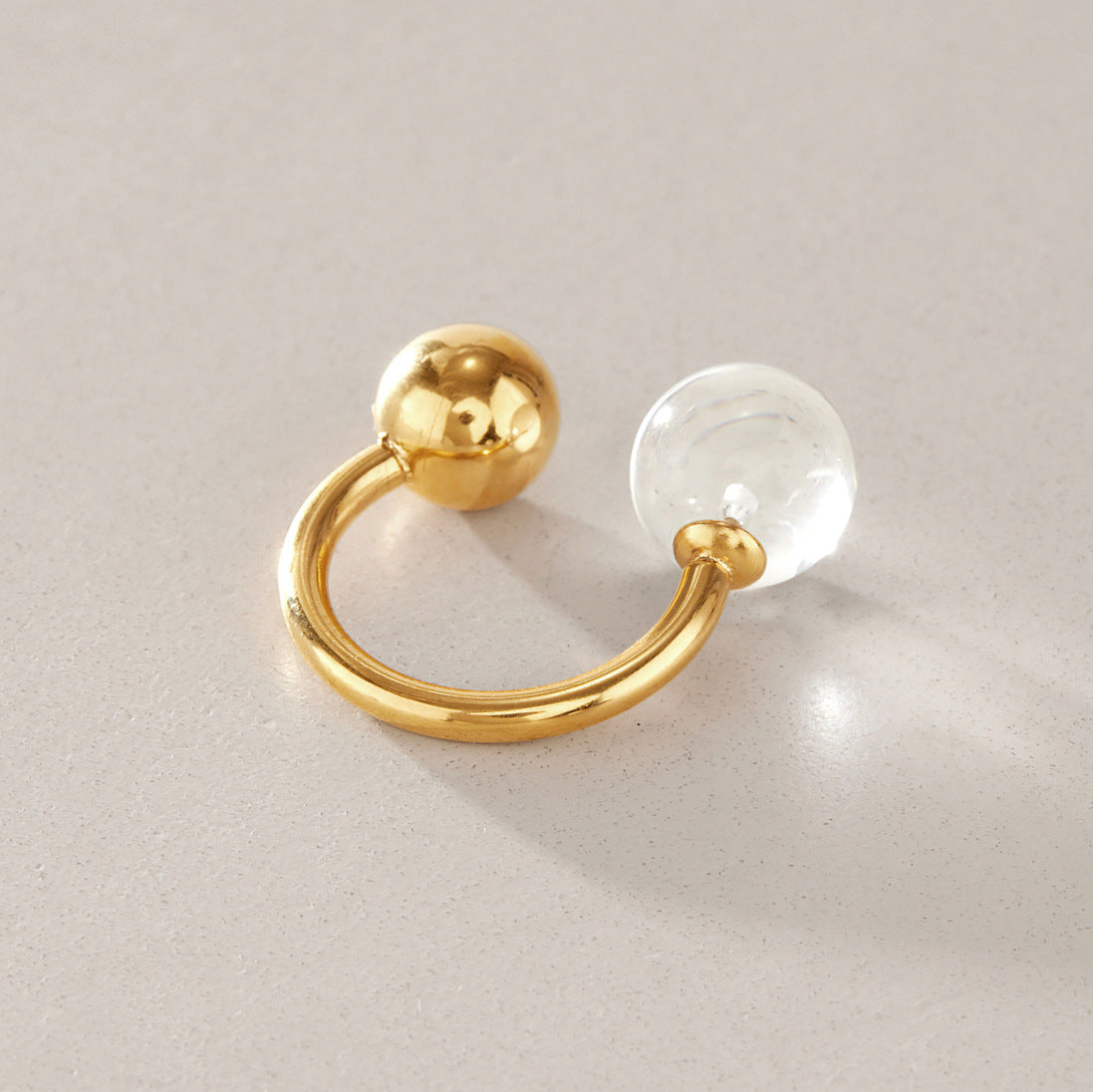 Gold tone open ring with clear resin ball and polished metal ball