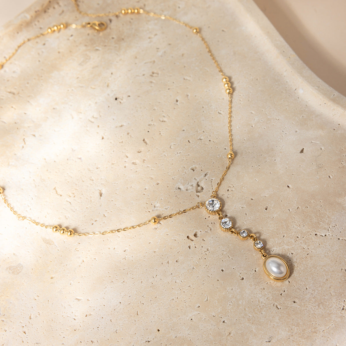 18K gold stainless steel zircon pearl Y necklace styled on neutral background